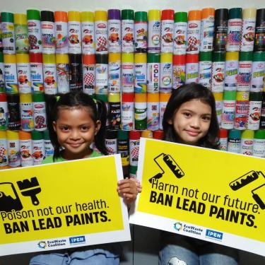 Two young kids holding yellow signs reading "Ban Lead Paints"