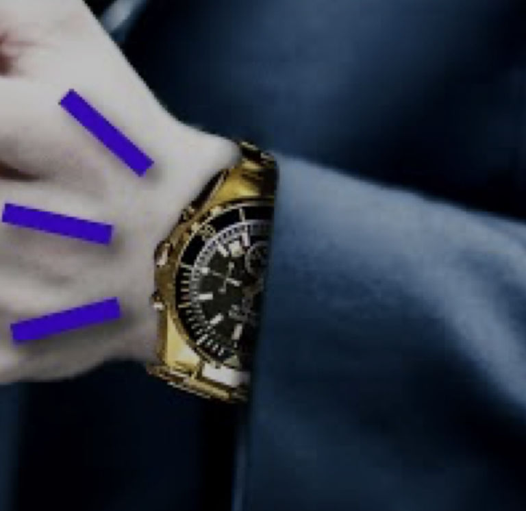 A person wearing a gold wristwatch on their left hand, with three blue lines drawn near the wrist, and dressed in a dark sleeve.