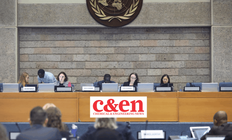 A panel of six people sit at a long table in front of a stone wall and a UN emblem, with C&EN Chemical & Engineering News displayed on the front. Audience members are visible in the foreground.