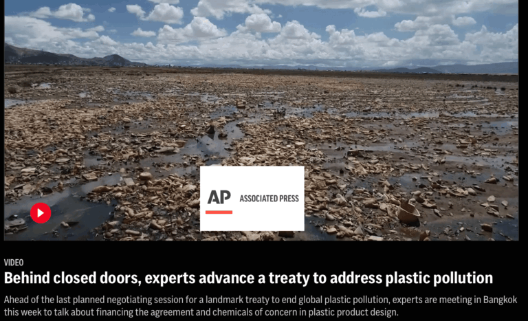 A vast, barren landscape is covered in plastic debris under a partly cloudy sky. In the background are distant mountains and a wide expanse of littered land. The Associated Press logo appears in the center of the image.