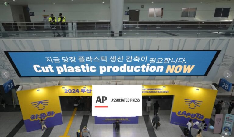 A large sign reads “Cut plastic production NOW” in English and Korean above a busy convention hall entrance with yellow banners for the 2024 Busan International Childrens Books Fair.