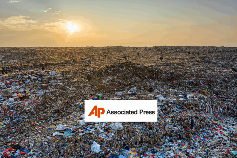 A vast landfill covered with piles of trash and scattered debris stretches to the horizon under a cloudy sky at sunset. Several small human figures are visible among the garbage. Associated Press logo at center.