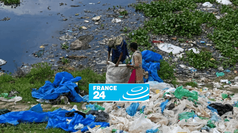 Two people collect plastic waste and garbage near a polluted body of water, with scattered debris and blue tarps on the grass. The France 24 logo is partially covering the lower center of the image.