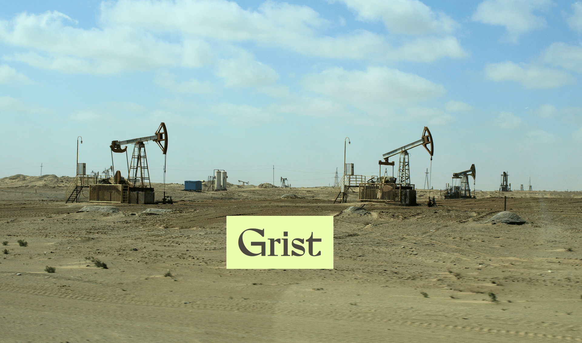 Oil pumpjacks operate in a flat, arid landscape under a partly cloudy sky. The word Grist appears in bold letters on a light-colored rectangle in the foreground.