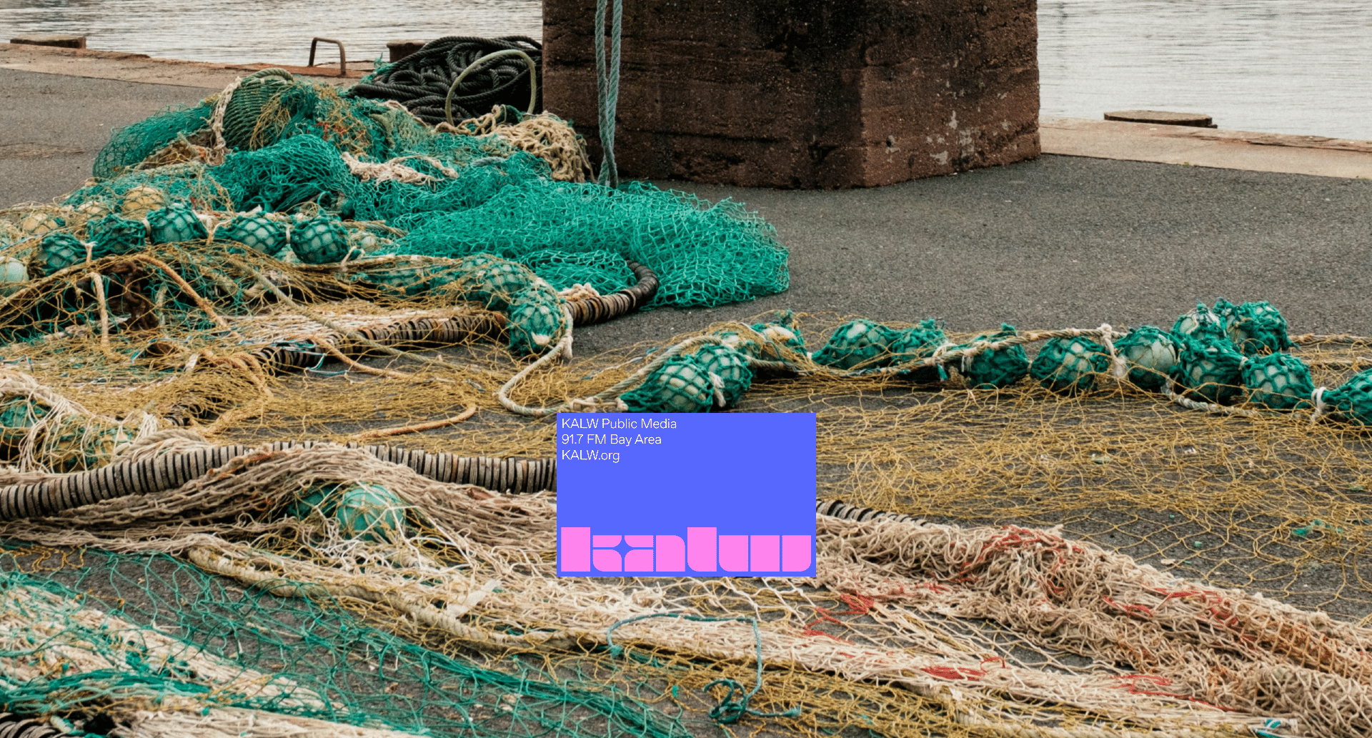 Fishing nets and ropes are spread out on a concrete dock near the water. A blue and pink graphic with text is overlaid on the image, partially covering the nets.