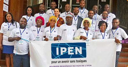 A group of people stand outside a building, wearing matching white shirts and name badges. They are holding a banner that reads IPEN pour un avenir sans toxiques with additional text below.