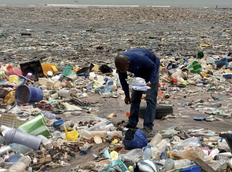 a man on a beach collecting plastic trash