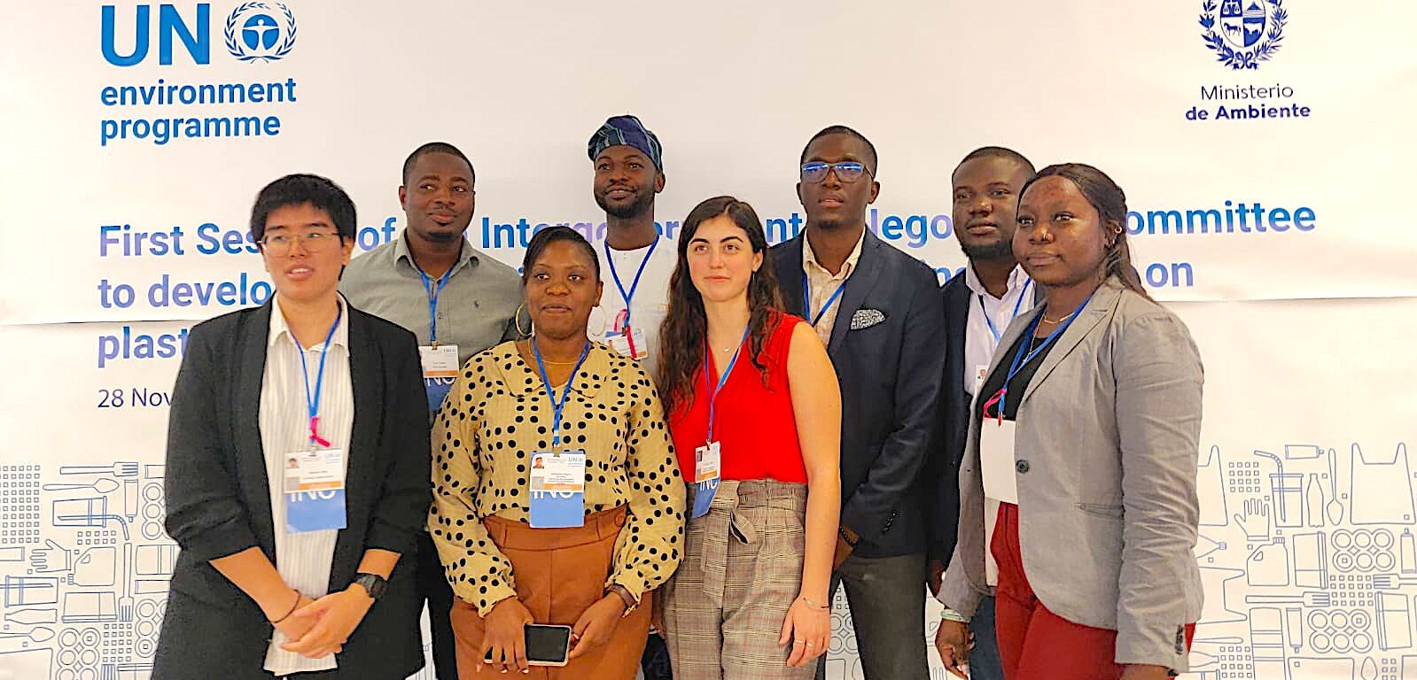 A group of eight people wearing conference badges stand in front of a banner for the UN Environment Programme and Ministerio de Ambiente at an event about developing a global agreement on plastic pollution.
