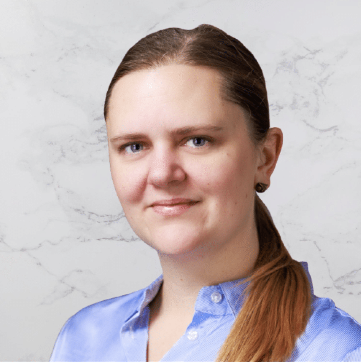 A woman with light skin and straight, light brown hair pulled back, wearing a light blue collared shirt, looks at the camera with a neutral expression. A white and gray marbled background is behind her.