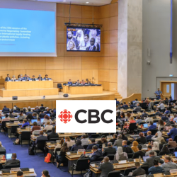 A large conference room is filled with attendees seated at rows of desks facing a stage with a panel of speakers. A large screen displays a UN presentation. The CBC logo is overlaid at the bottom center of the image.