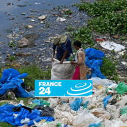 Two people collect plastic waste and garbage near a polluted body of water, with scattered debris and blue tarps on the grass. The France 24 logo is partially covering the lower center of the image.