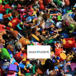 A large pile of assorted colorful plastic toys and figurines scattered closely together, with a white rectangular card in the center displaying the logo DAILY NATION.